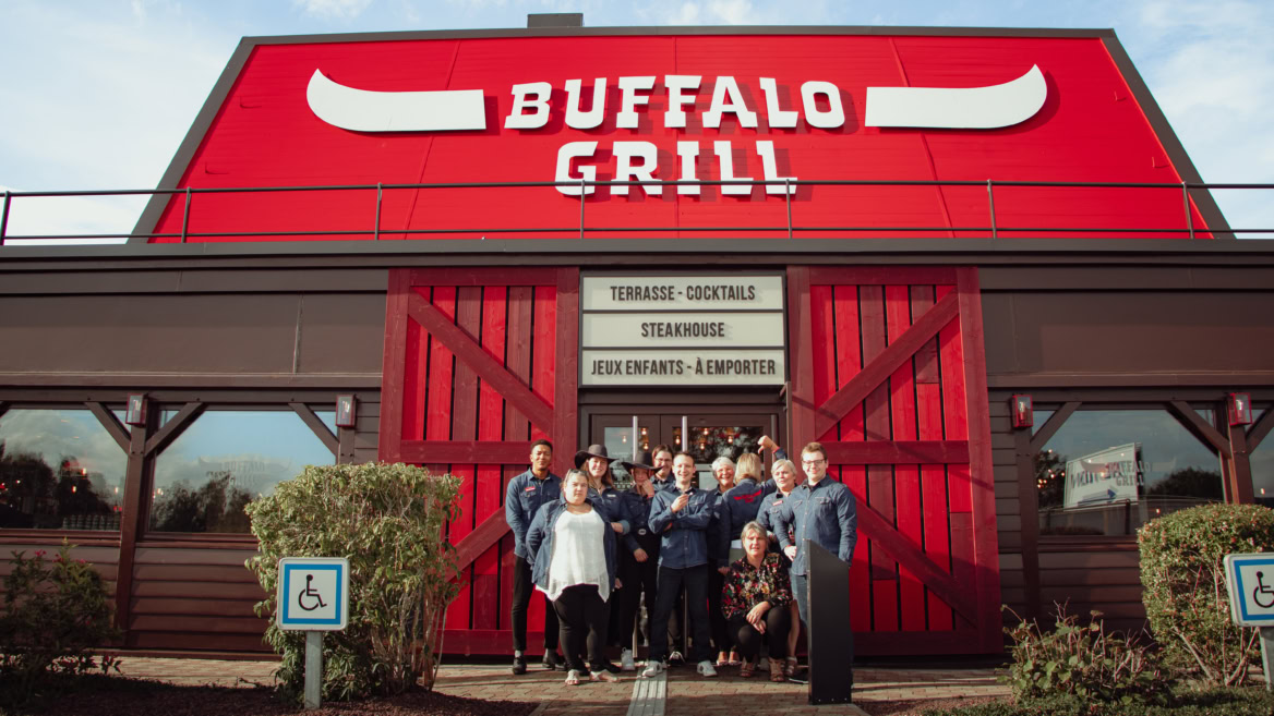 Equipe posant devant un restaurant Buffalo Grill